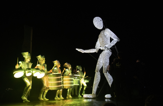 This is a photo of Dundu, a 5-metre-high puppet, with drummers in light-up costumes