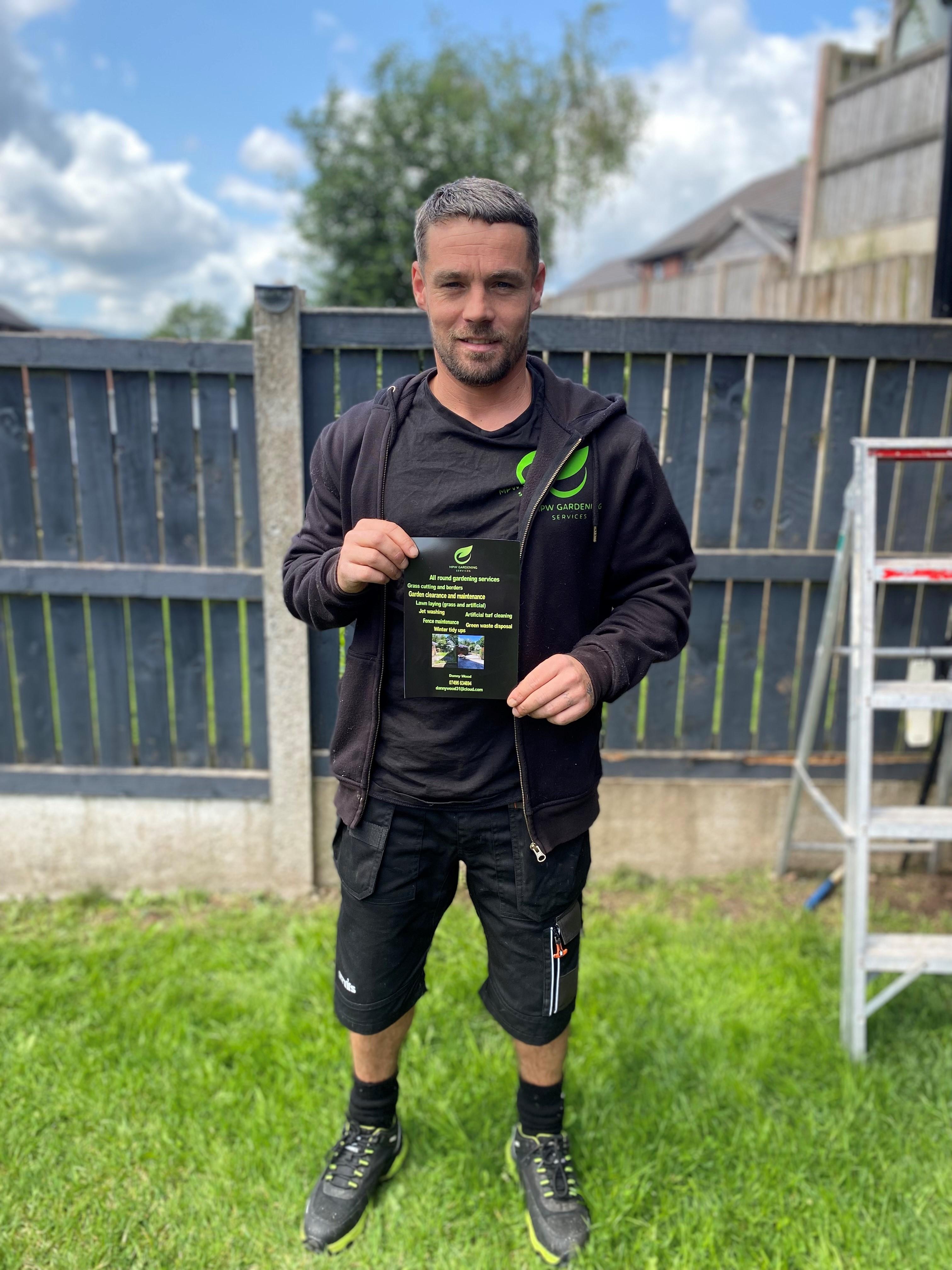 Happy Workshop Customer in his companies&#039; PW Gardening Uniform holding a PW Gardening flyer.