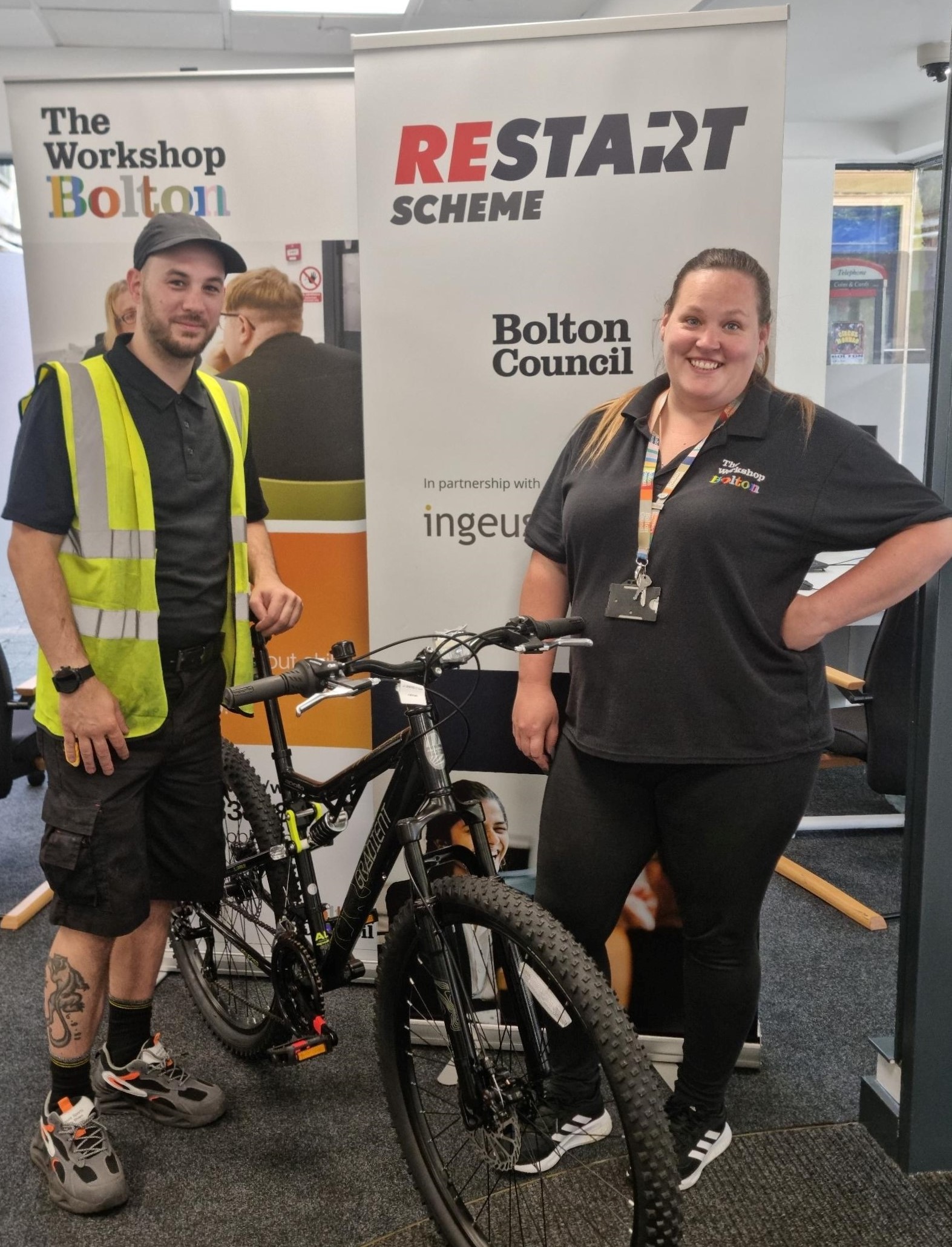 Participant L stood with his bike smiling and workshop adviser stood with him