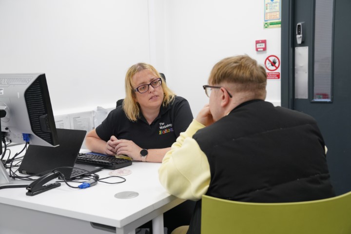 Workshop advisor listening to customer in the foreground at their desk