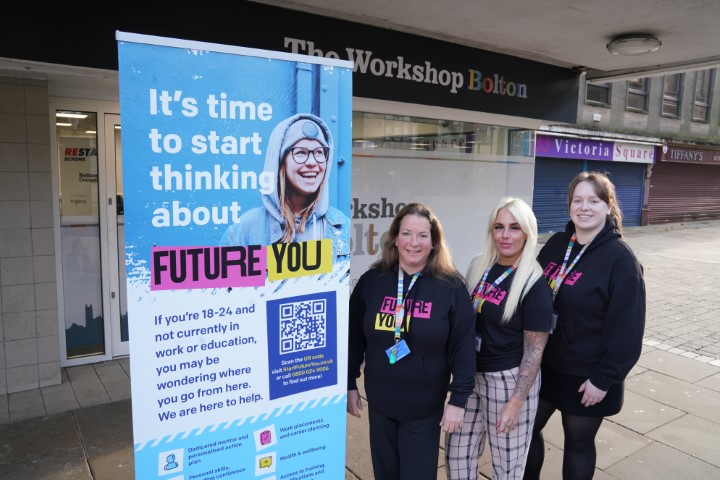 Three FutureYou team members, stood outside the workshop bolton office, next to a blue FutureYou banner